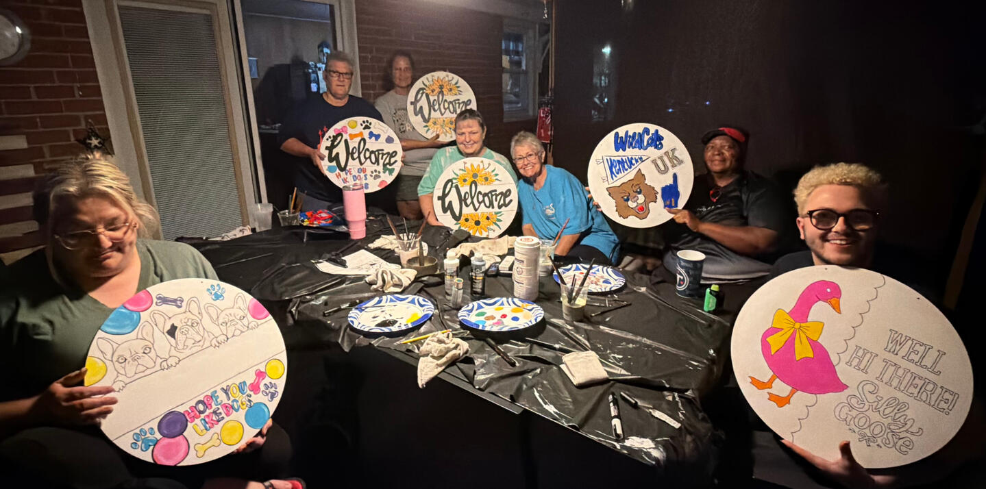Friends enjoying a private Art & Aperture paint party in Central City, Kentucky, creating personalized painted signs together for a fun group celebration.