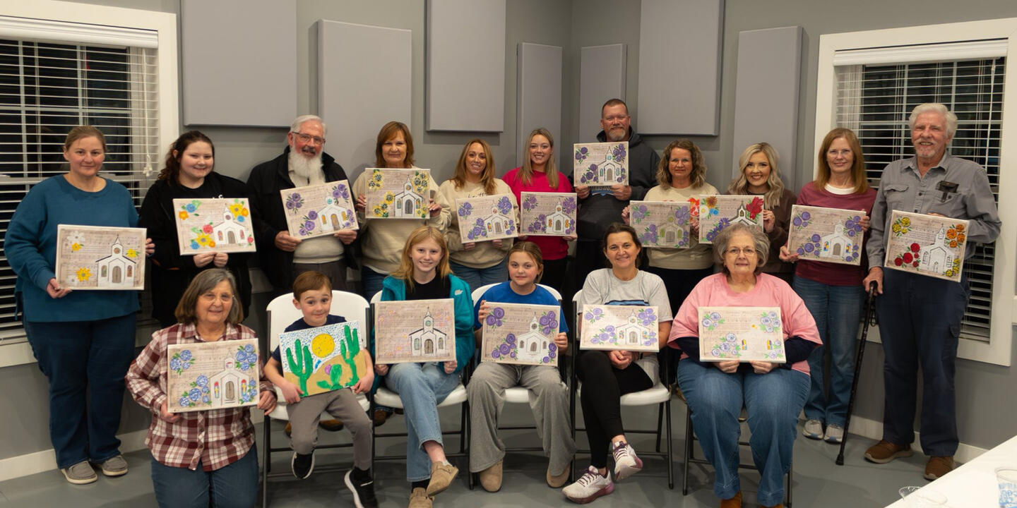 Church group members of all ages showing their finished canvas paintings after an Art & Aperture paint party in Greenville, Kentucky.